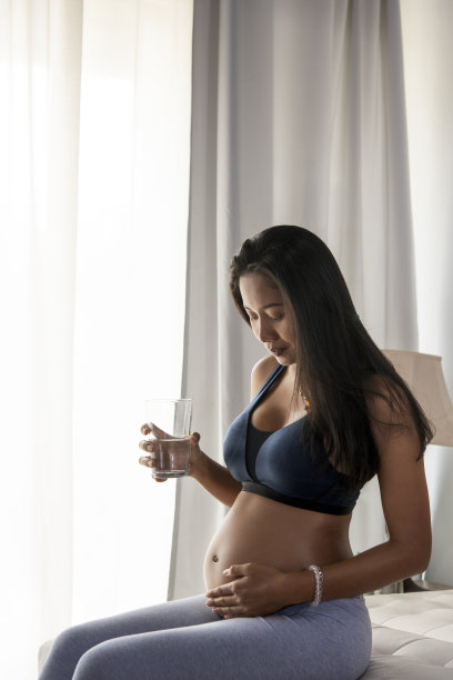 5个月的孕妇准备成为母亲喝干净的水，为母亲和孩子的健康在胃里。孕妇的概念。图片下载