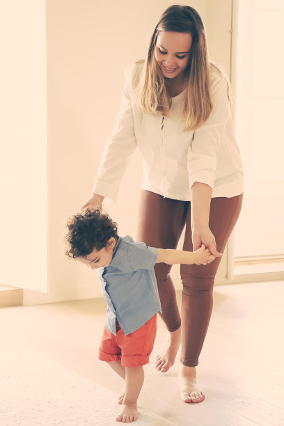 幸福的白人母亲牵着儿子的手，帮他走路图片下载