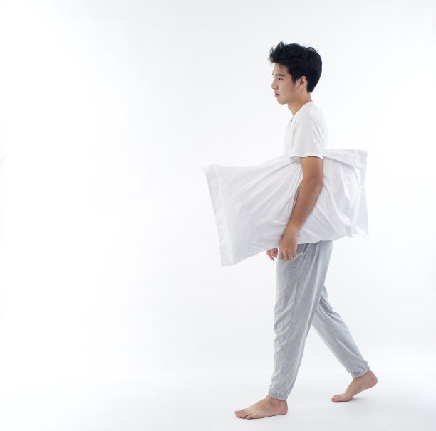 睡意朦胧的年轻人抱着白色背景上的枕头图片下载