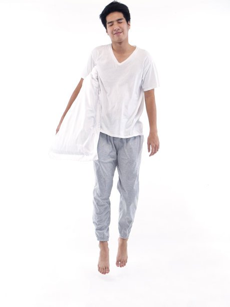 穿着睡衣的年轻人拥抱着白色背景上的枕头图片下载