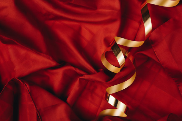 抽象概念艺术的红色丝绸或缎背景与金色缎带。聚会或生日的想法与复制空间。图片下载