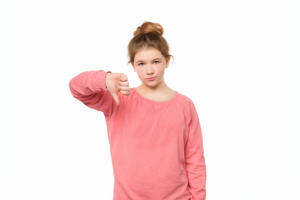 不高兴的少女孤立在白色背景显示拇指向下与消极的表情图片下载