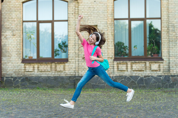 精力充沛的小女孩听着音乐蹦蹦跳跳耳机，积极的生活理念图片下载
