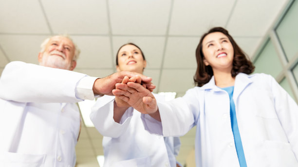 医院里手牵手的医护人员队伍。团体医生协调双手为成功工作。卫生保健的概念图片下载