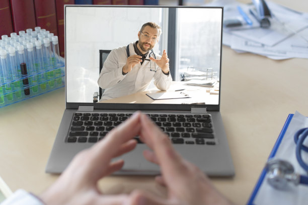 一个医生在一个在线视频通话的笔记本电脑显示器前的照片。与同事的对话图片下载
