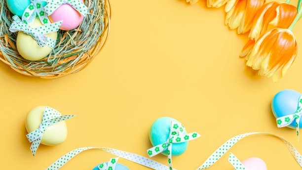 复活节背景黄色。彩色的彩蛋与丝带，春天的郁金香，羽毛在柔和的黄色背景在快乐复活节装饰。平躺，俯视图。图片下载