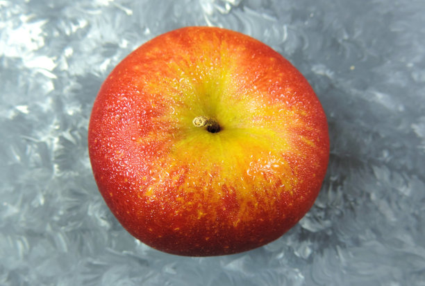 新鲜的红黄苹果滴在抽象的灰白色背景下，健康的素食零食图片下载