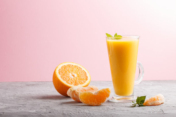 一杯橙汁在灰色和粉红色的背景。早晨，春天，健康饮品的概念。侧视图，拷贝空间。图片下载