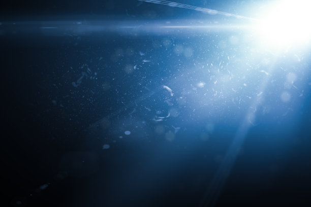 在深蓝色背景下的光和灰尘颗粒图片下载