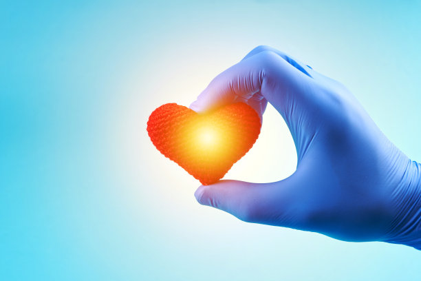 在蓝色背景上，医务人员双手举着心形标志。心脏病学的概念。心脏药物的概念图片下载