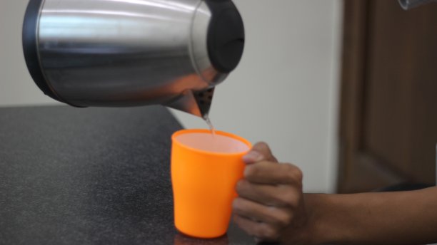 一个人往杯子里倒水的照片图片下载