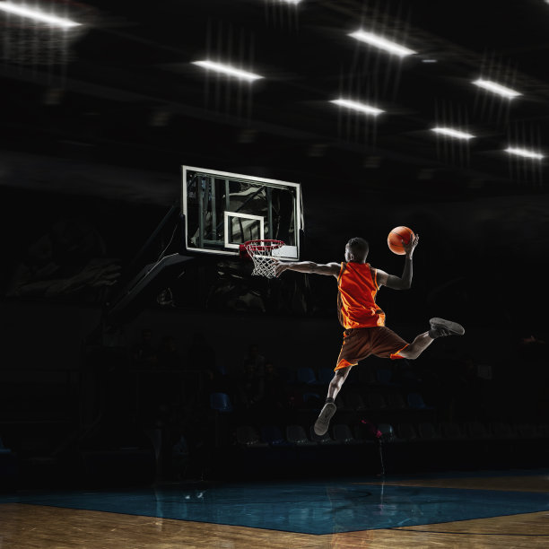 非裔美国青年篮球运动员在行动和手电筒在体育馆的背景。运动的概念，运动，能量和动态，健康的生活方式。图片下载
