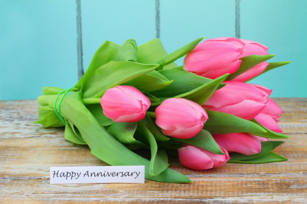 周年快乐卡片，木质表面上有一束粉红色的郁金香图片下载