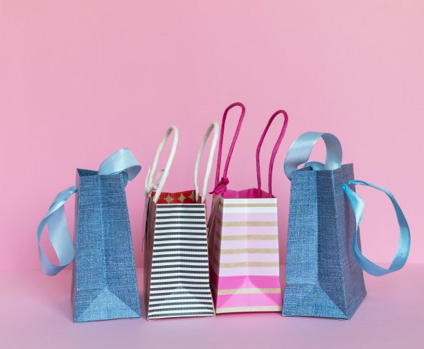 粉红色背景的彩色纸袋。购物的概念或销售的季节。图片下载