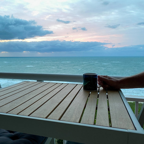 一张桌子上的咖啡杯，上面是大西洋上生机勃勃的日出图片下载