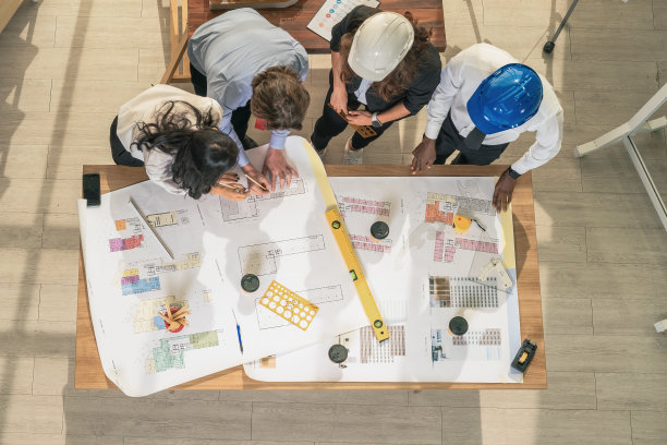 建筑和工程业务背景的建筑师和工程师项目开发团队头脑风暴，并在建筑师办公室与项目平面图一起工作图片下载