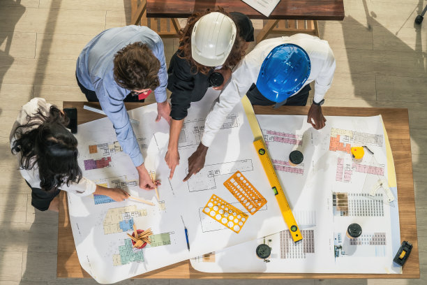 建筑和工程业务背景的建筑师和工程师项目开发团队头脑风暴，并在建筑师办公室与项目平面图一起工作图片下载
