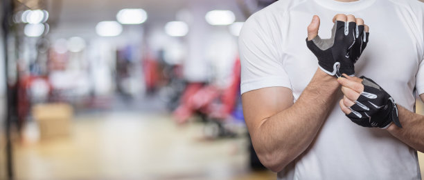 运动员戴着健身手套在体育馆的背景上。图片下载