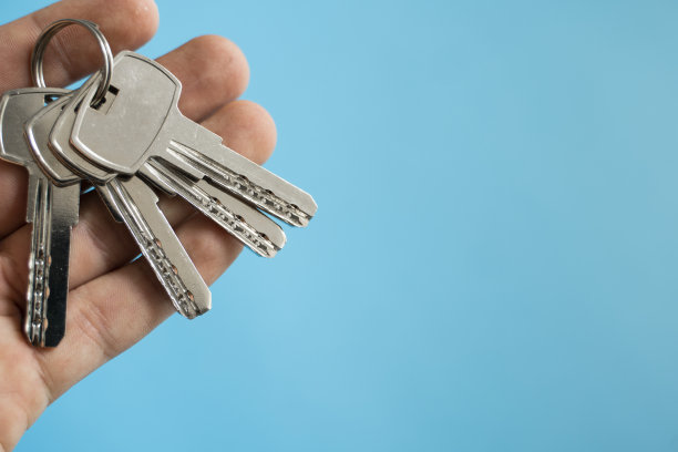 男人手里拿着一串蓝色背景的钥匙。有房子钥匙的房地产经纪人。专注于按键。房地产经纪人手里拿着一串钥匙。图片下载