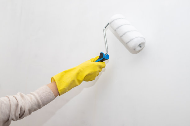 工人的手与油漆滚轴漆墙内公寓近距离。修理房子。维修保养理念图片下载