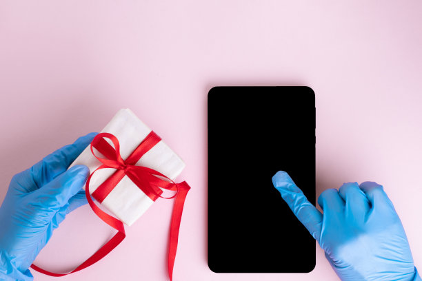 一只戴着蓝色防护手套的手按在一块黑黑的屏幕上的写字板上，一只戴着防护手套的手拿着一份礼物图片下载