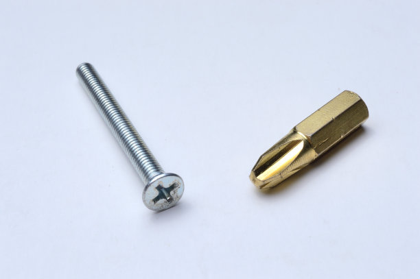 一个金色的比特和一个螺栓躺在一个明亮的背景特写。图片下载