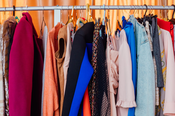 在更衣室的架子上挂着一套色彩鲜艳的衣服。在现代精品店衣架上的衣服。挂在衣架上的衣服，特写图片下载
