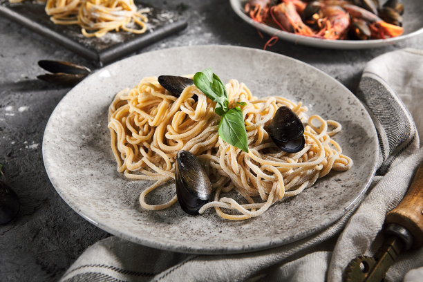 用海鲜和绿叶自制的意大利面。灰色复古的桌子和布料。美味的贻贝意大利面图片下载