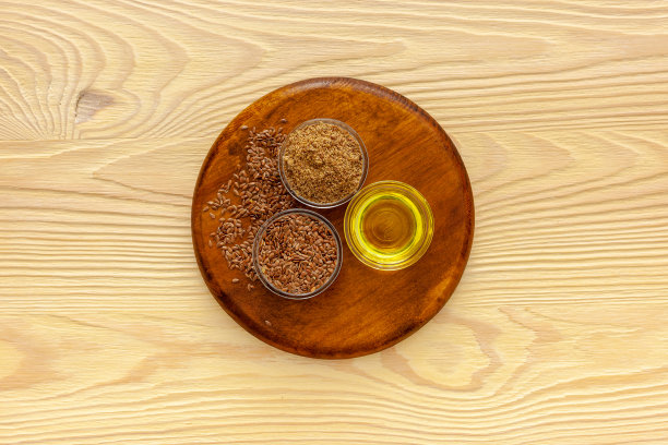 用勺子和碗盛亚麻籽，配上一瓶亚麻籽油和亚麻籽面粉图片下载