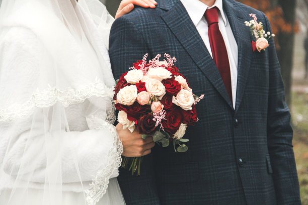 新娘和新郎一起靠近。新娘捧着婚礼花束。结婚礼服和红领带。图片下载