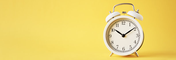 黄色背景上的白色复古闹钟，带有复制空间的长横幅图片下载