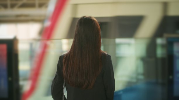 年轻的女商人站在地铁站台上，背影。图片下载
