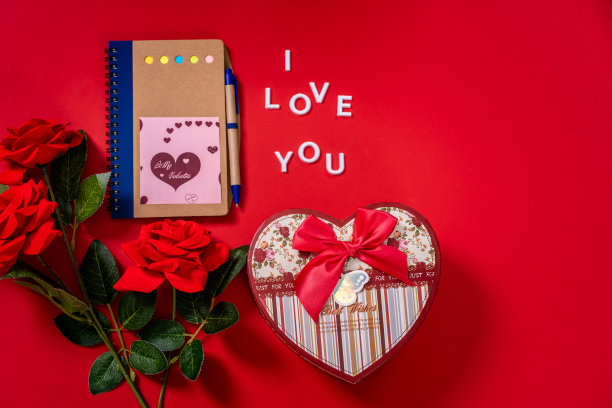 我爱你的字句，心形的盒子，带钢笔的空白记事本，红色背景上的红玫瑰。拷贝空间为情人节图片下载