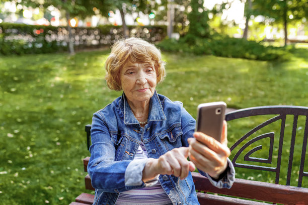 一位高级女士在摆姿势自拍。科技，沟通和人的概念-高级女性与智能手机。老年人的日常生活。图片下载
