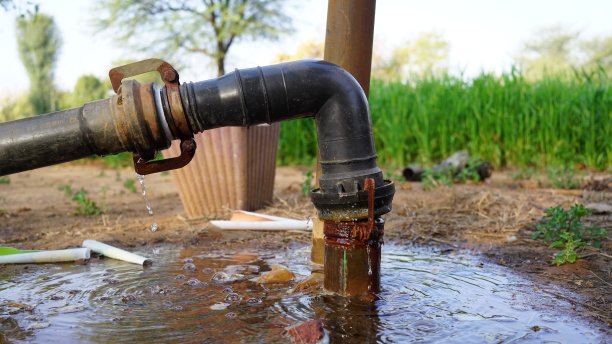 黑色塑料弯管在印度农地特写。大量的水被浪费掉了。图片下载