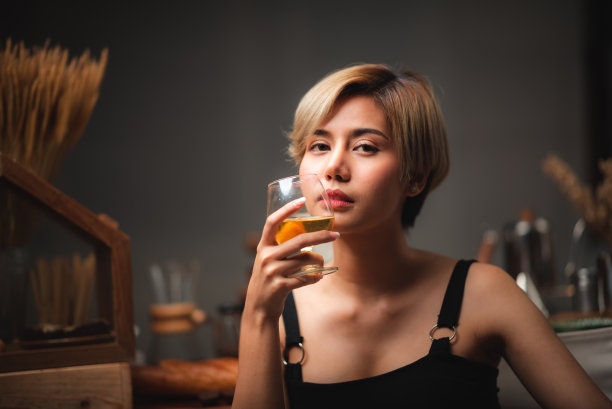 迷人的酒保女孩手里拿着新鲜的鸡尾酒在吧台庆祝图片下载