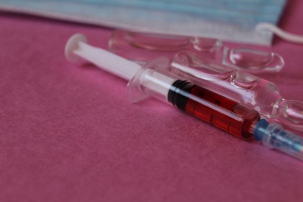 粉红色背景上带药血瓶的药物接种注射器图片下载