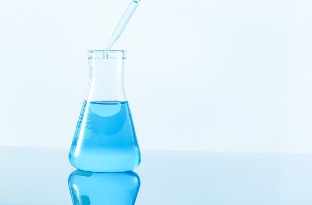 将蓝色液体滴入白色背景的实验室玻璃器皿中图片下载
