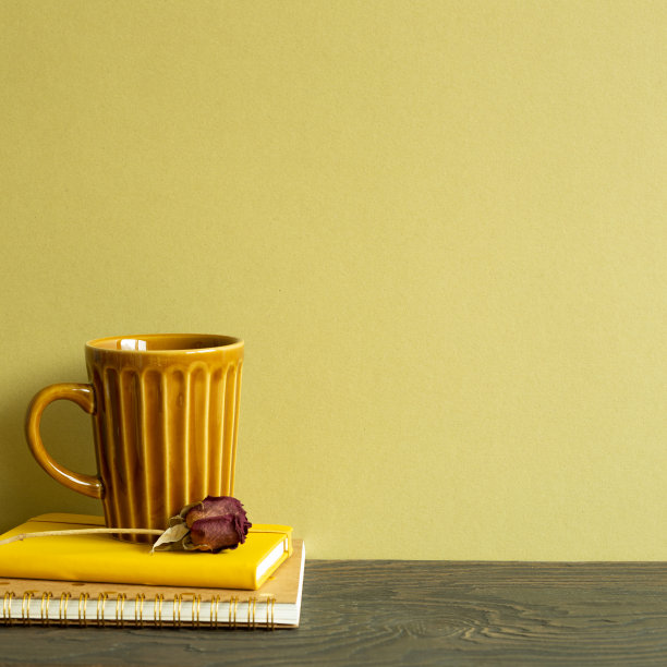 笔记本，马克杯，木桌上的干玫瑰。卡其色背景图片下载