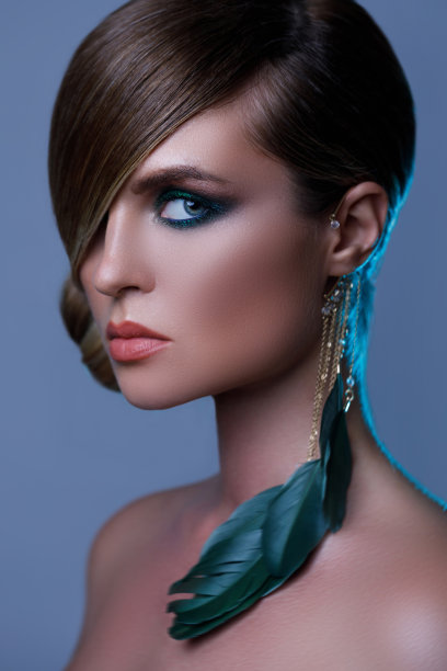 模特时尚的形象，光滑的头发覆盖一只眼睛和羽毛耳环图片下载