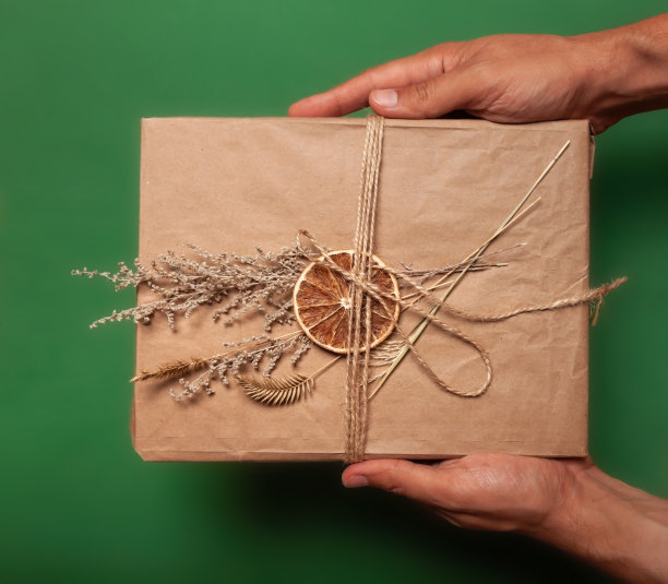 手工制作的礼品盒，用牛皮纸包装，用干花装饰。在绿色backround。海报和横幅模板平铺照片与复制空间图片下载