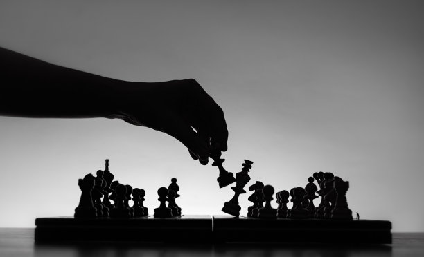 国际象棋的游戏。棋盘与棋子的剪影在白色的背景。商业理念、竞争和战略理念的概念。黑白经典艺术照片。图片下载