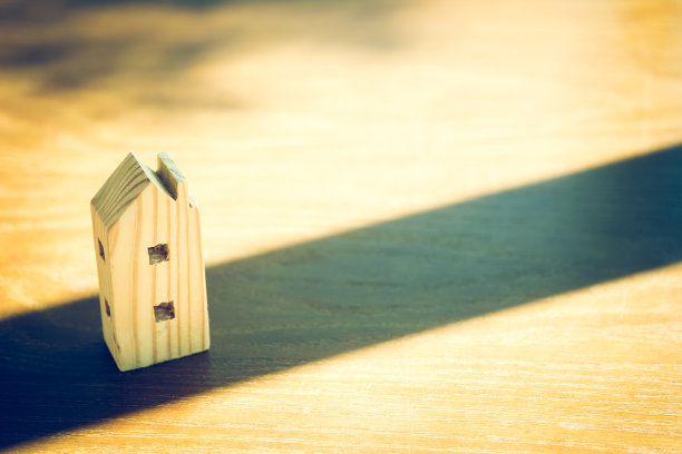 房子的木制模型放在桌子上，在晨光中有窗户的阴影图片下载