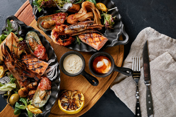 烤海鲜拼盘。什锦美味的烤海鲜配蔬菜。烤杂烩狗杂种配辣椒酱和蔬菜。黑色背景图片下载