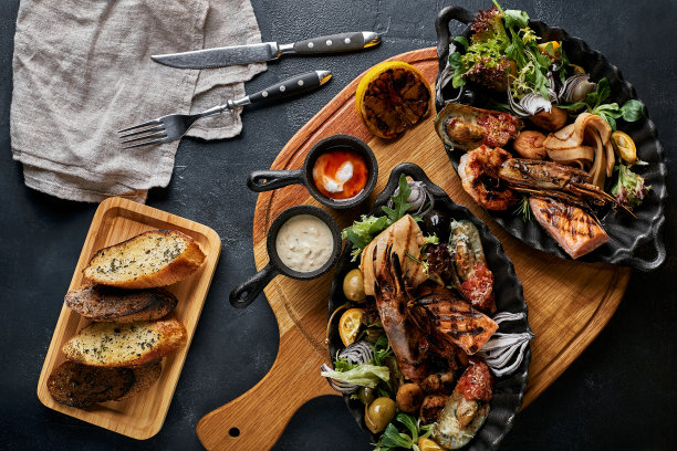 烤海鲜拼盘。什锦美味的烤海鲜配蔬菜。烤杂烩狗杂种配辣椒酱和蔬菜。黑色背景图片下载