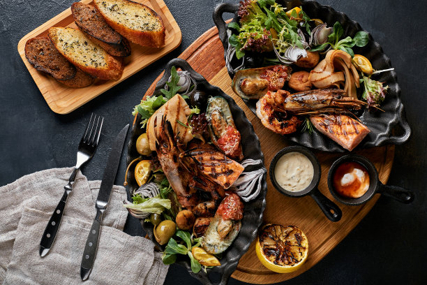 烤海鲜拼盘。什锦美味的烤海鲜配蔬菜。烤杂烩狗杂种配辣椒酱和蔬菜。黑色背景图片下载