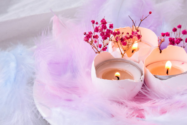 由白色蛋壳组成，里面有蜡烛。烛光。用鸟羽毛装饰的明亮的复活节装饰。柔和的颜色。复活节贺卡图片下载