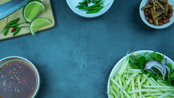 Yum芒果照片俯视图食物安排。辛辣的沙拉食物，上面有油炸的坚果和脆皮鱼。主要原料是生芒果、酸橙汁、鲜辣椒粉、鱼露、糖混合而成。让酸味带来。图片下载
