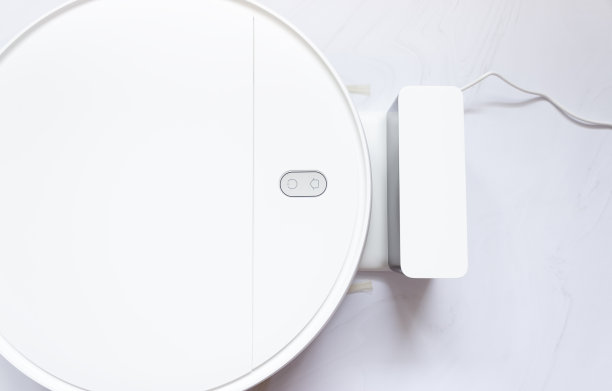 白色机器人吸尘器和充电器的一部分，俯视图。图片下载