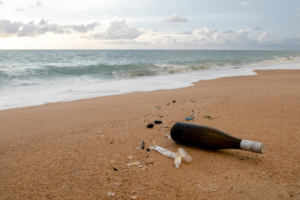 环境问题的概念，棕色的饮料瓶和沙滩上的碎片。图片下载